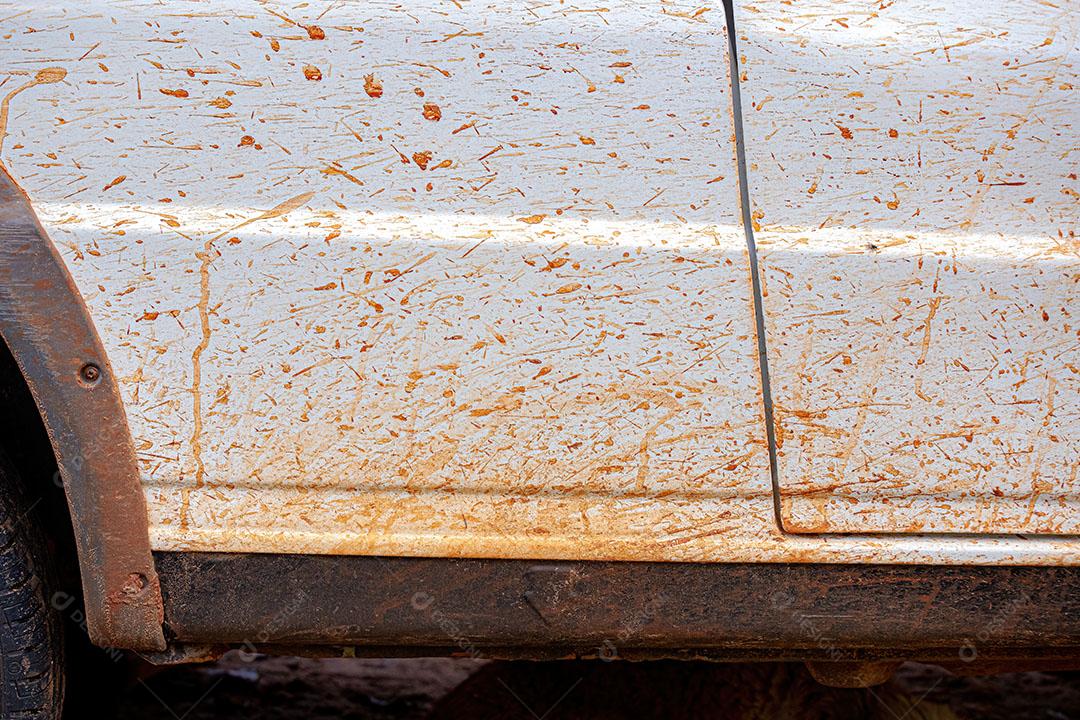Carro Branco Sujo de Respingos de Lama Andando na Estrada de Terra após a Chuva JPG