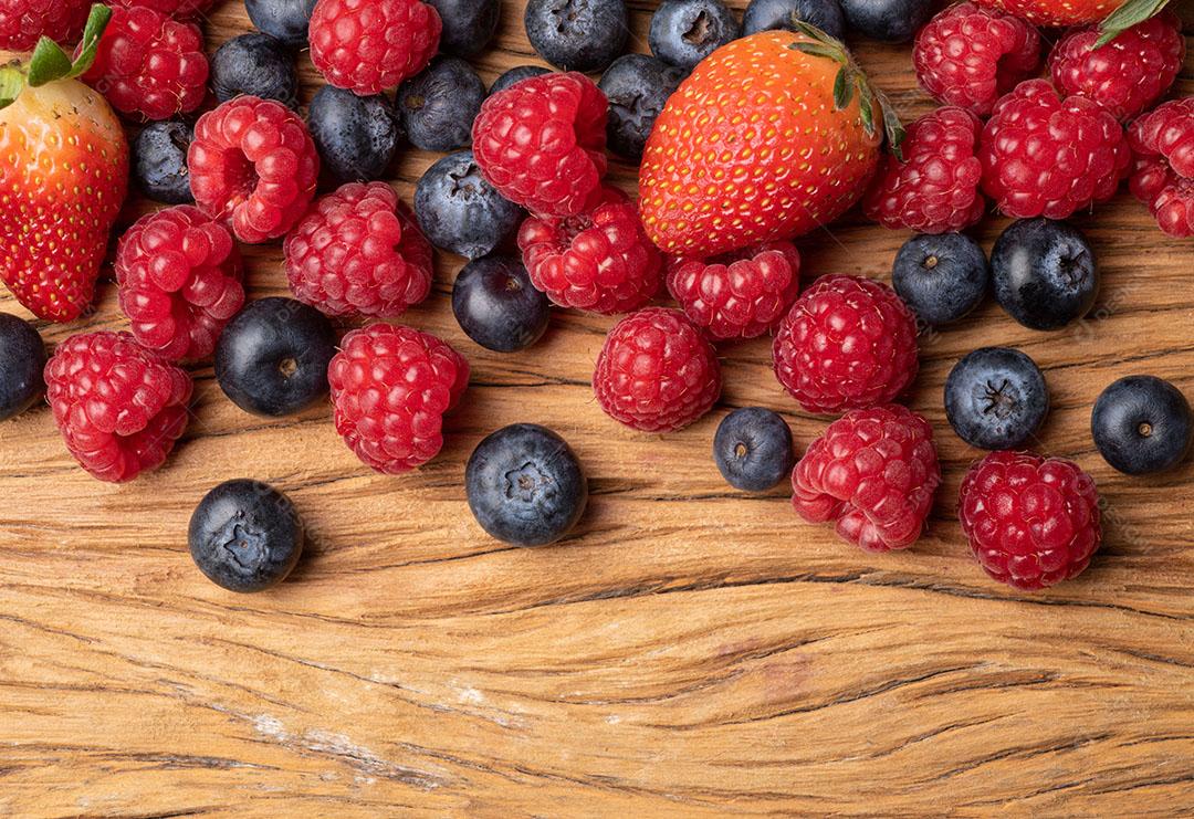 Framboesas, Morangos e Mirtilos Sobre Mesa de Madeira Imagens jpg
