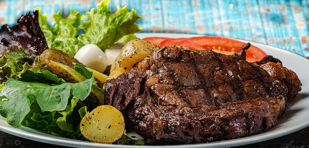 Foto Picanha Grelhada Servida Batata Assada Picles e Tomate Rúcula e Salada de Palmito