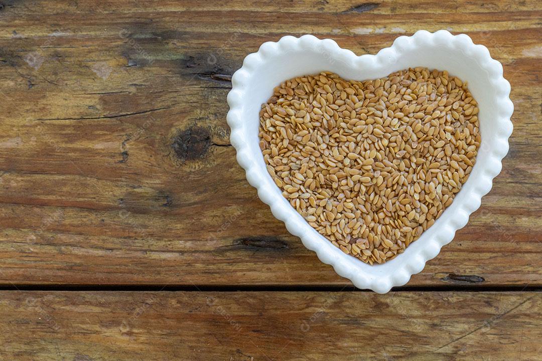 Linhaça Dourada em uma Tigela em Forma de Coração em uma Mesa de Madeira JPG