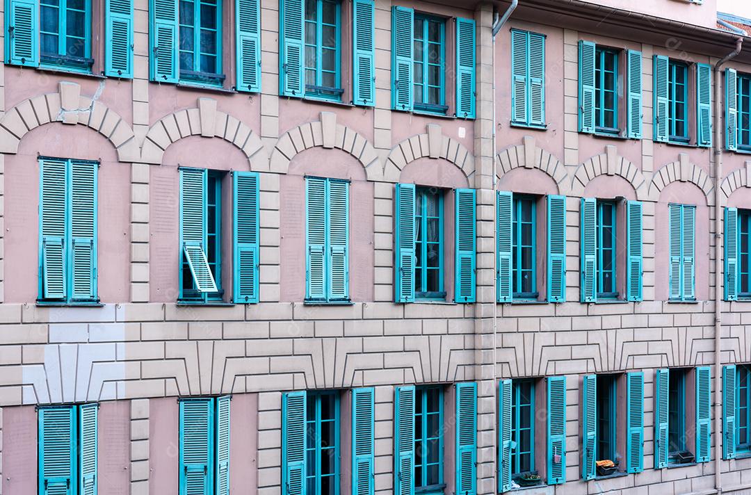 perspectiva de prédio rosa velho com janelas verdes no center