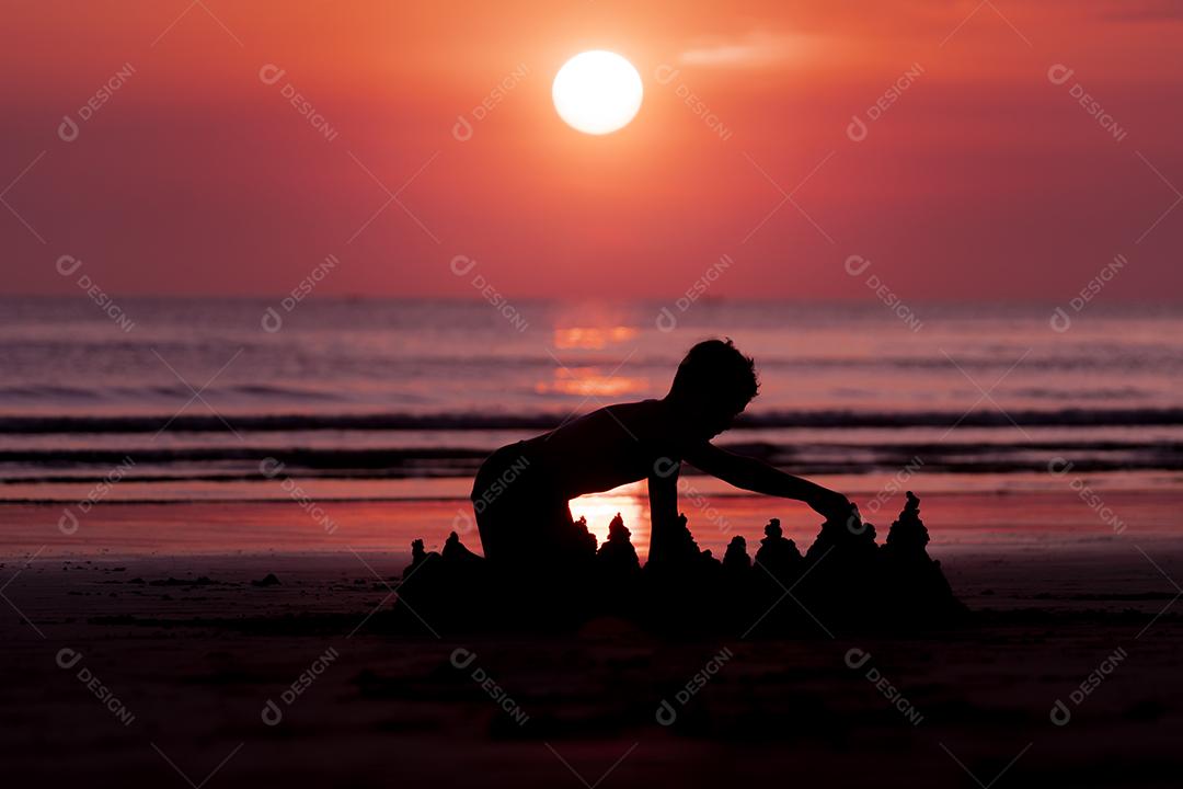 Criança construindo castelos de areia em uma praia Imagem JPG