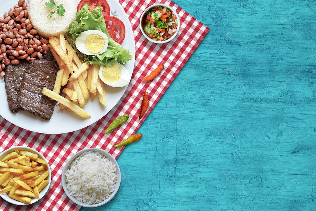 Prato de Comida Brasileira Feijão Arroz Carne Batata Frita e Salada Fundo Azul Imagem JPG