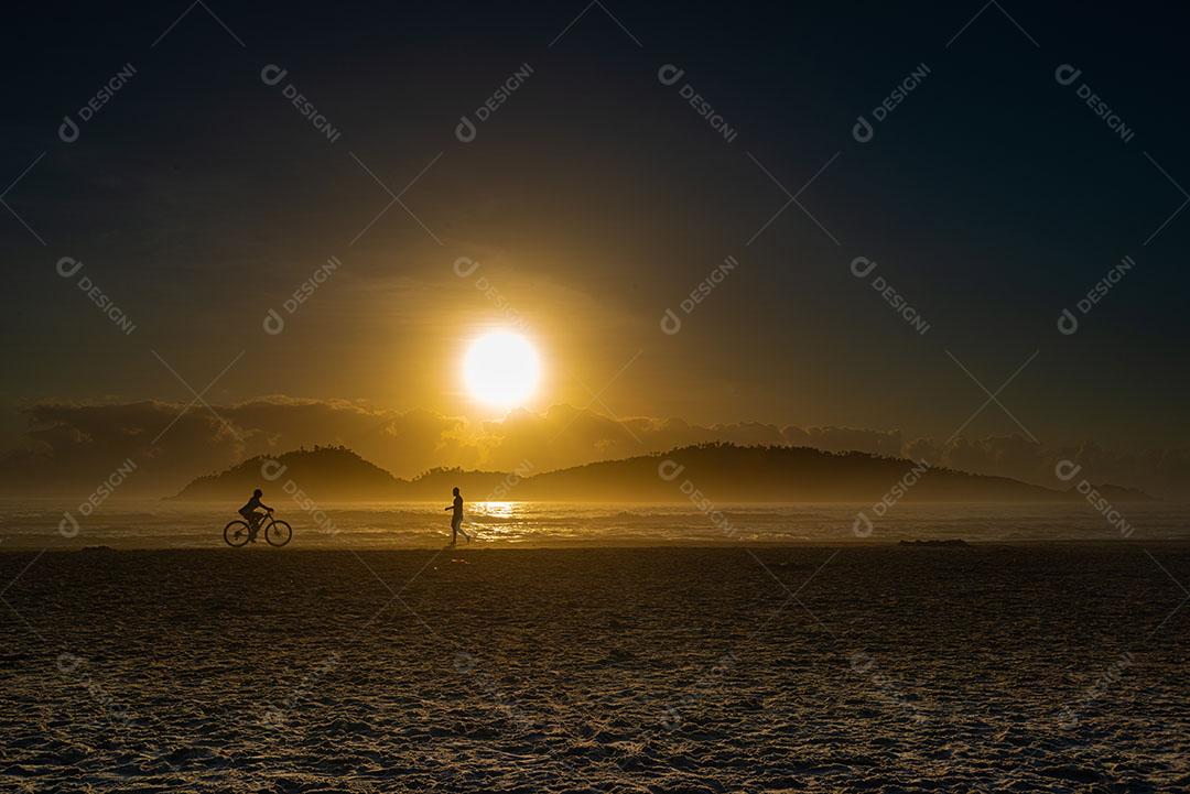 Silhueta de Um Ciclista e Um Caminhante Fazendo Atividade Física na Praia Imagem JPG