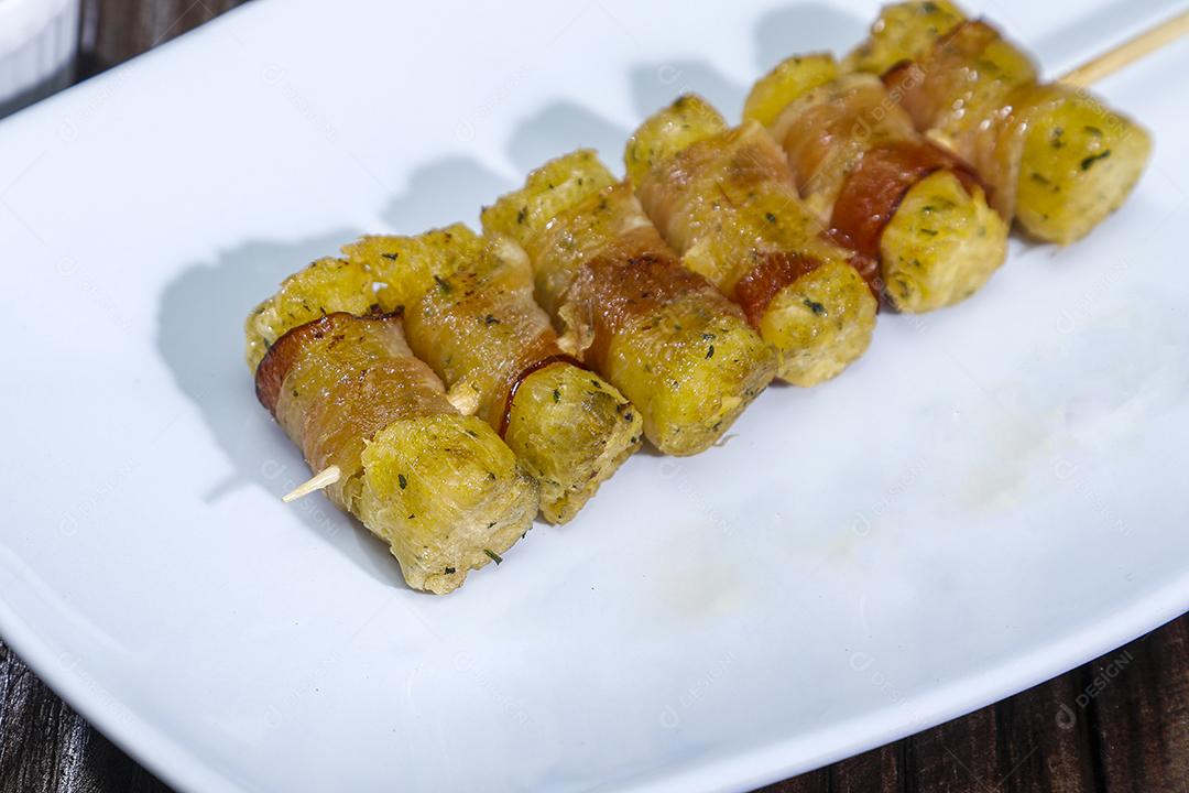 Espetinhos de mandioca enrolados no bacon medalhão de mandioca Imagem JPG