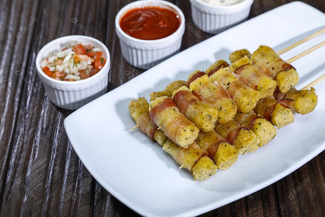 Espetinhos de mandioca enrolados no bacon medalhão de mandioca Imagem JPG