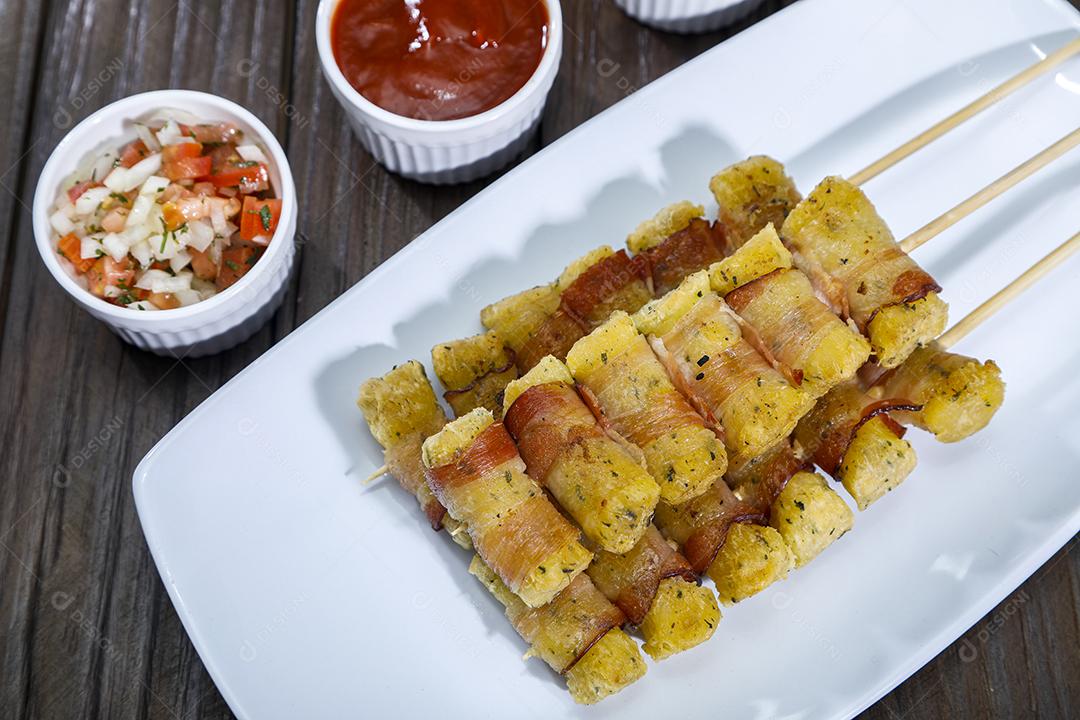 Espetinhos de mandioca enrolados no bacon medalhão de mandioca Imagem JPG