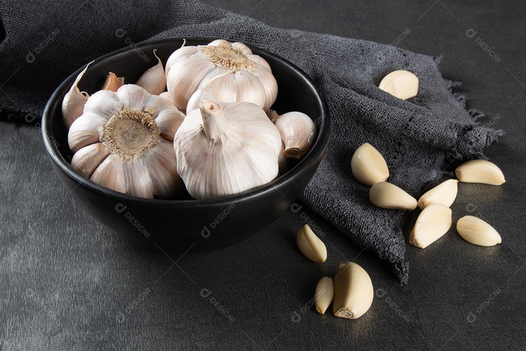 Dentes de Alho e Bulbo Em Tigela Preta Em Tecido e Fundo Escuro Imagem JPG