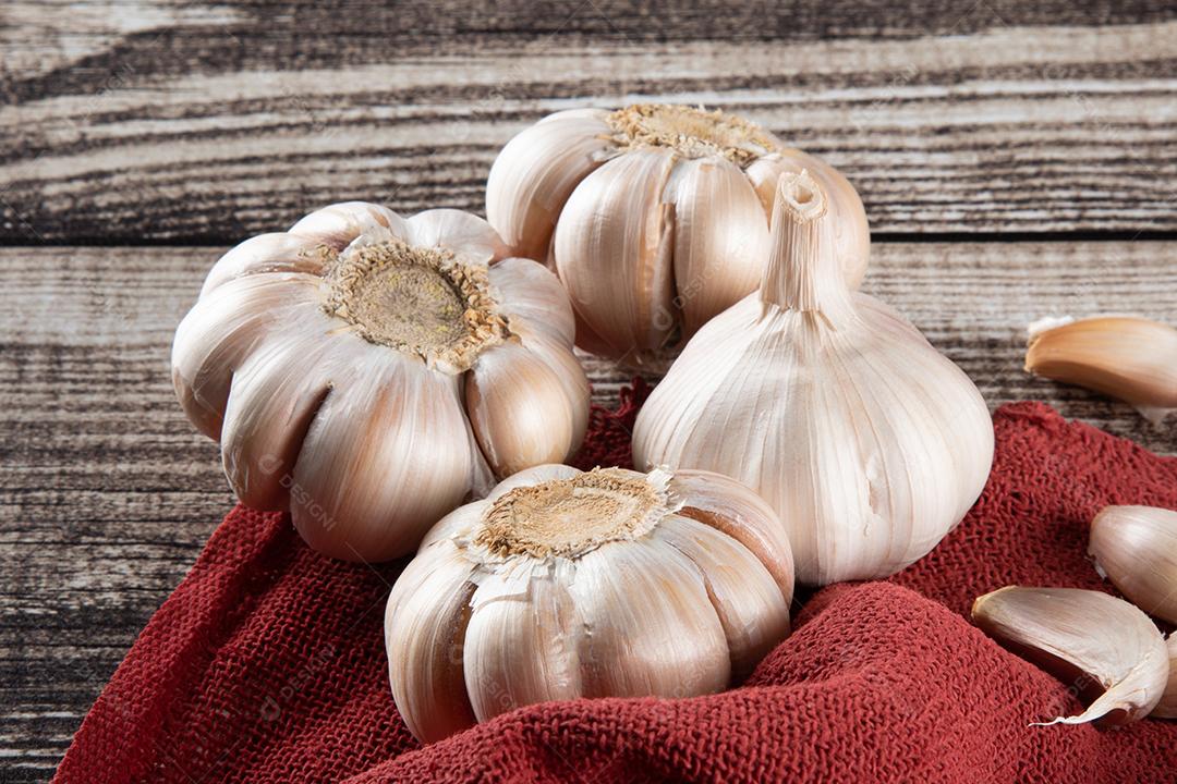 Dentes de Alho e Bulbo na Mesa de Madeira e Tecido Vermelho Imagem JPG