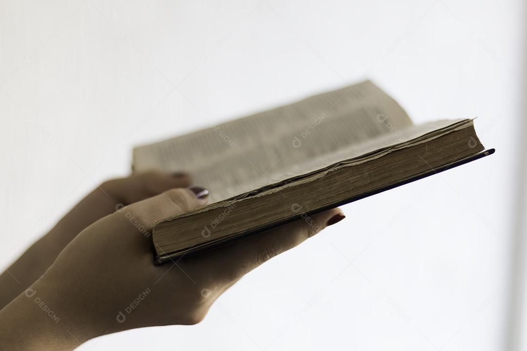 Mãos Segurando a Bíblia Sagrada Aberta e Orando Imagem JPG