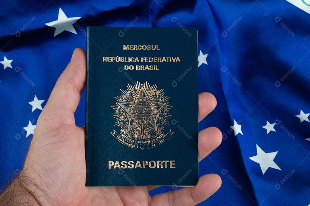 Mão Segurando Passaporte Brasileiro Com Bandeira Brasileira Ao Fundo Imagem JPG