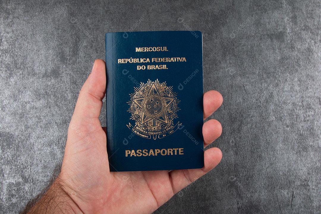 Mão Segurando Passaporte Brasileiro Com Bandeira Brasileira Ao Fundo Imagem JPG