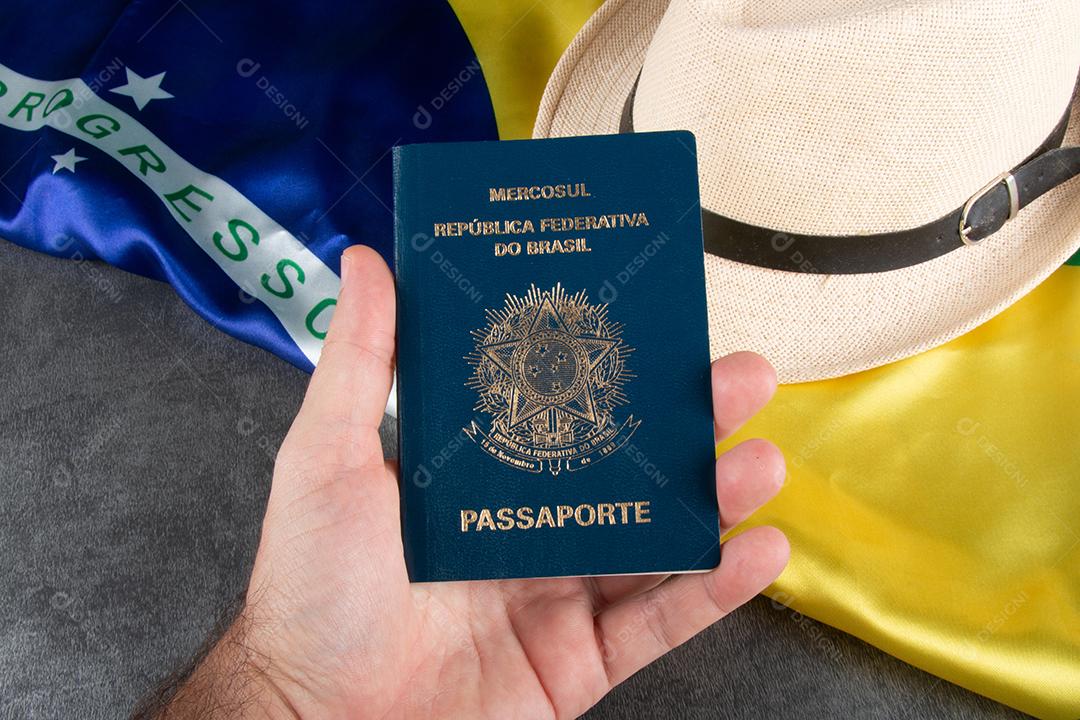 Mão Segurando Passaporte Brasileiro Com Bandeira Brasileira Ao Fundo Imagem JPG
