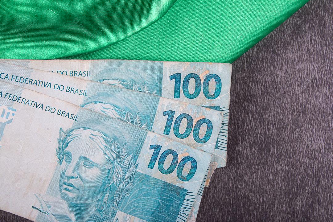 Foto Notas de Cem Reais na Bandeira Brasileira