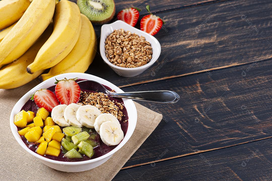 Açaí brasileiro em uma tigela acompanhada de frutas tropicais JPG