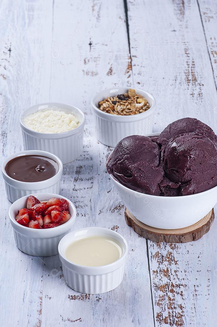 Açaí congelado em copo plástico e tigela branca com frutas JPG