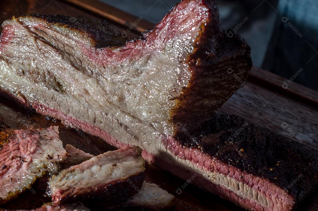 Carne assada sendo cortado sobre uma tabua de madeira churrasco