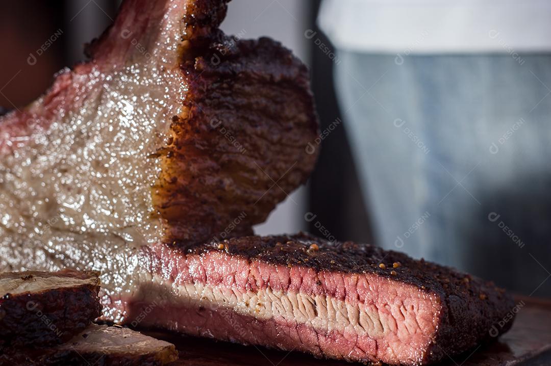 Carne assada sendo cortado sobre uma tabua de madeira churrasco