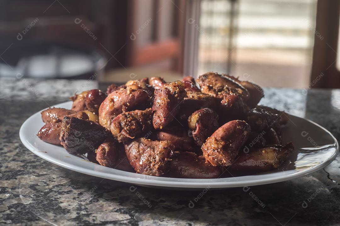 Coração de frango em um prato branco com fundo escuro Imagem JPG