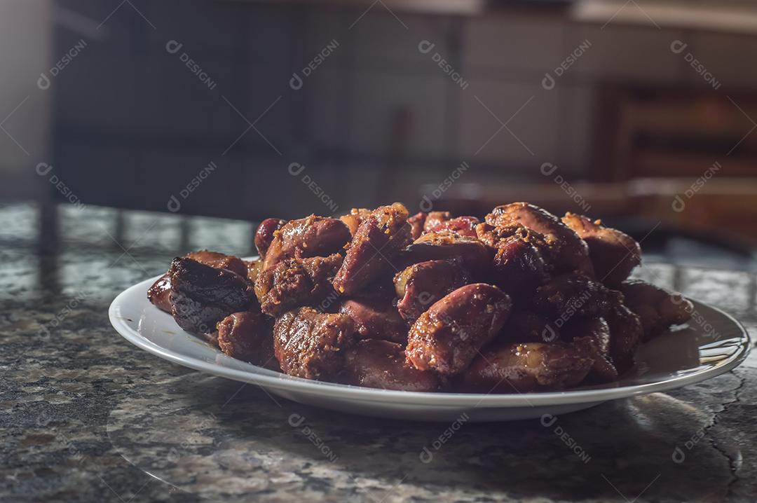 Coração de frango em um prato branco com fundo escuro Imagem JPG