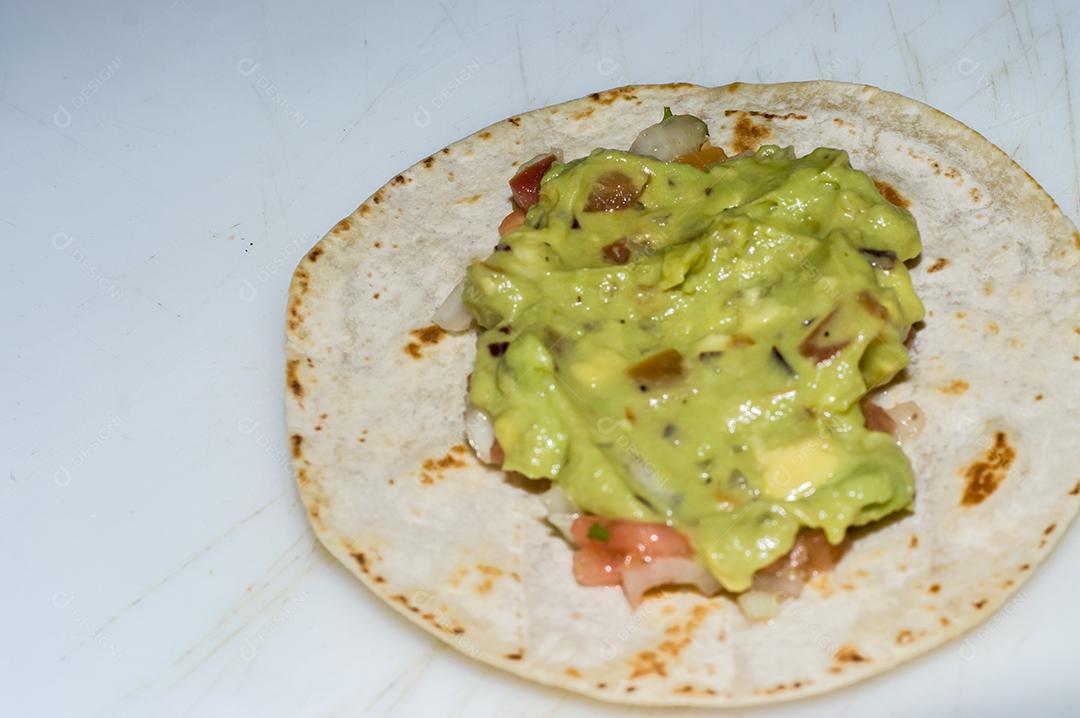 Shredded pork skewers with tortilla chips, guacamole and maemore background