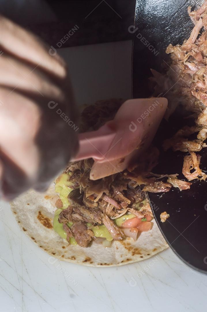 Espetinho de porco desfiado com tortilha, guacamole e fundo de maemore