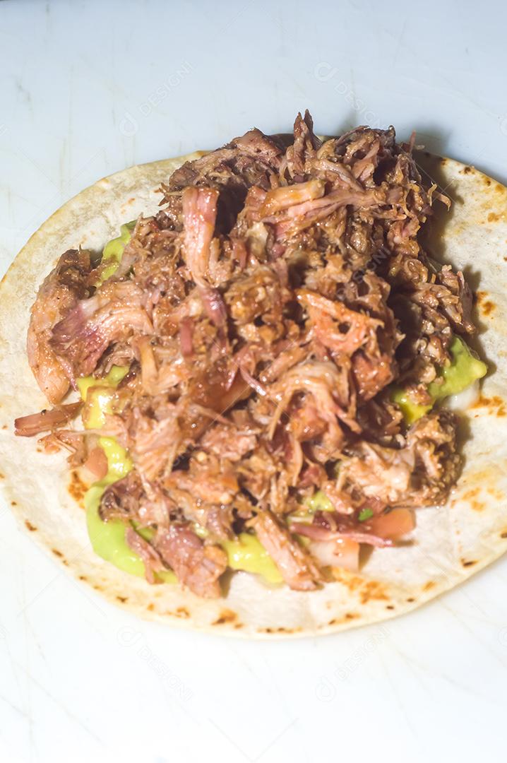 Espetinho de porco desfiado com tortilha, guacamole e fundo de maemore