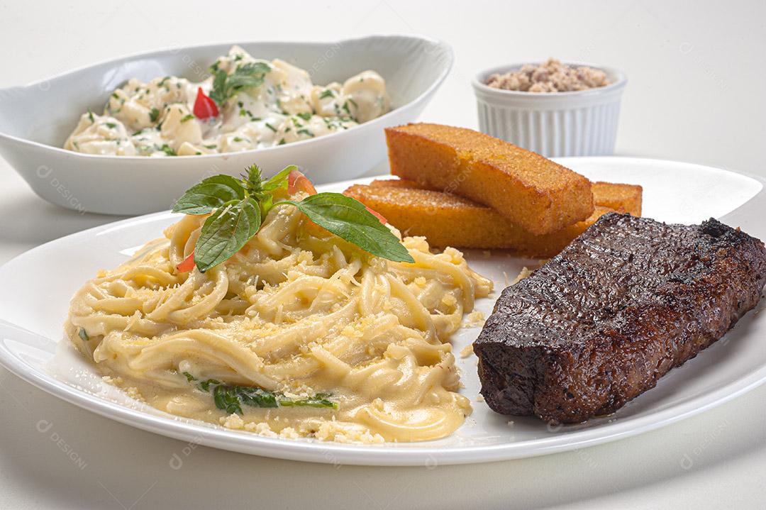 Espaguete de quatro queijos servido com filé e polenta frita, sirva