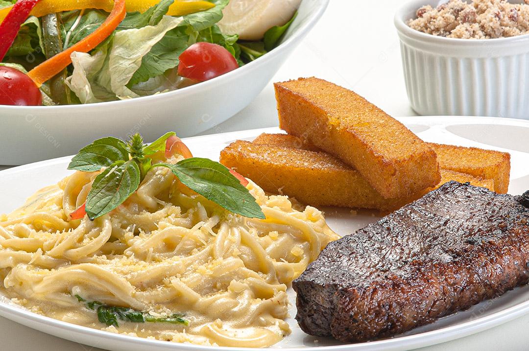 Espaguete de quatro queijos servido com filé e polenta frita, sirva