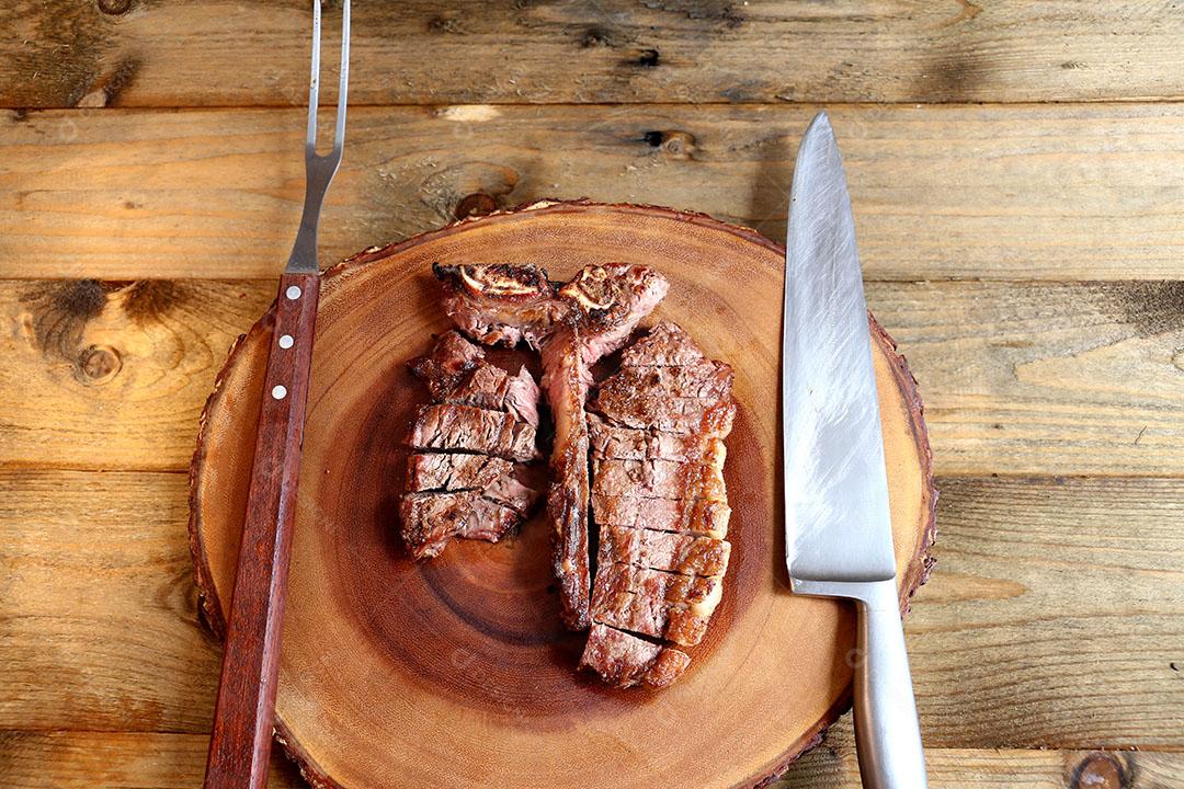 Foto Bife Grelhado na Grelha Com Osso e Dois Tipos de Carne Em Fundo de Madeira