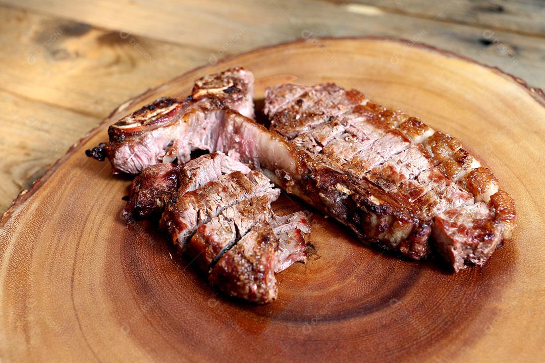 Foto Bife Grelhado na Grelha Com Osso e Dois Tipos de Carne Em Fundo de Madeira