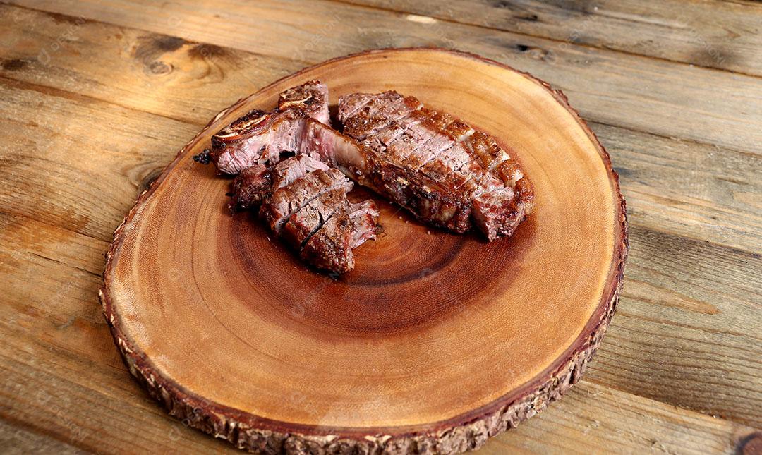 Foto Bife Grelhado na Grelha Com Osso e Dois Tipos de Carne Em Fundo de Madeira