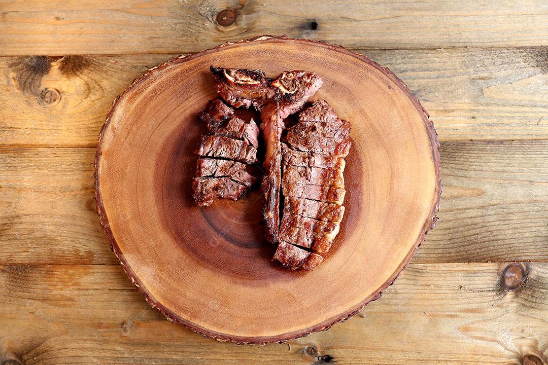 Foto Bife Grelhado na Grelha Com Osso e Dois Tipos de Carne Em Fundo de Madeira
