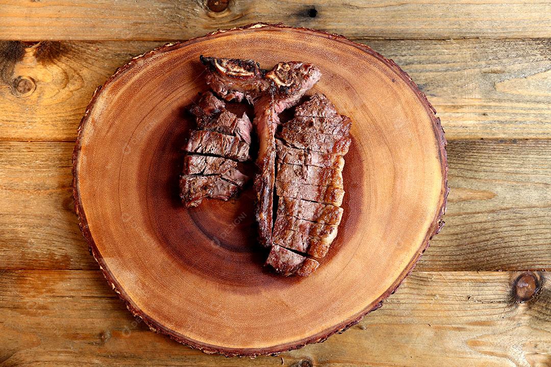 Foto Bife Grelhado na Grelha Com Osso e Dois Tipos de Carne Em Fundo de Madeira