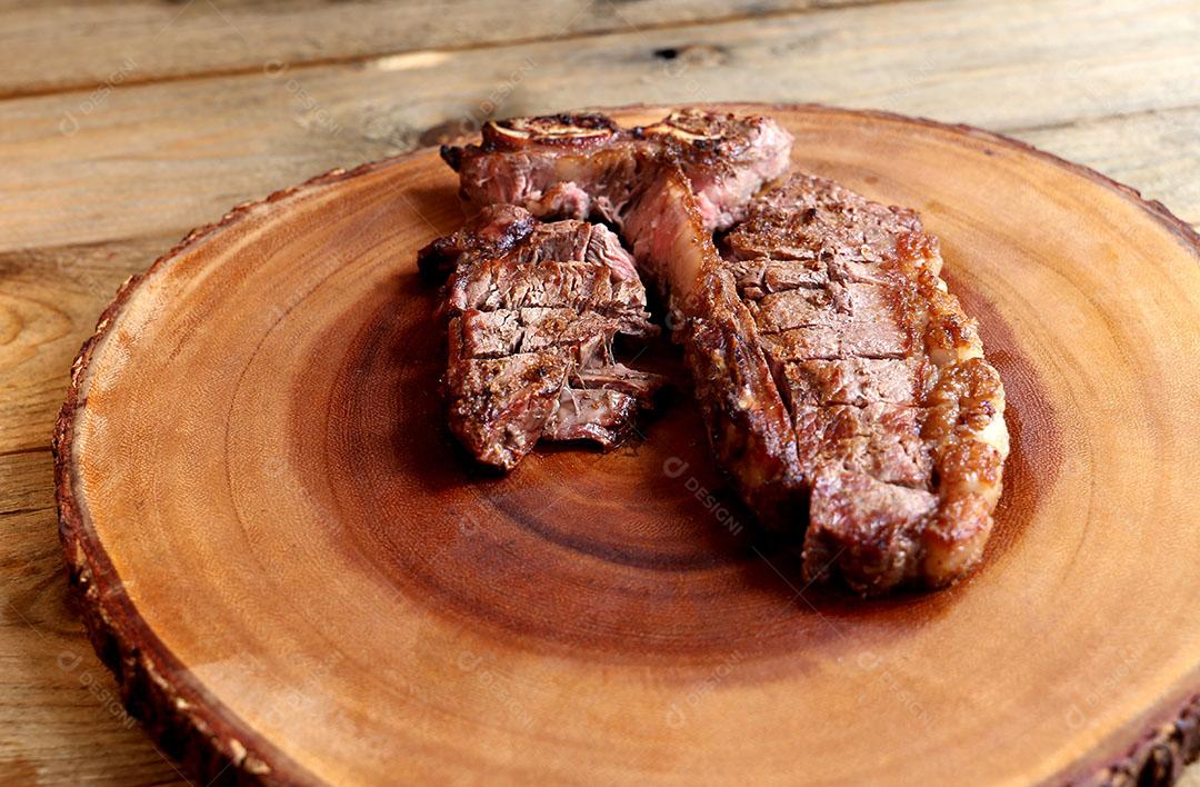 Foto Bife Grelhado na Grelha Com Osso e Dois Tipos de Carne Em Fundo de Madeira