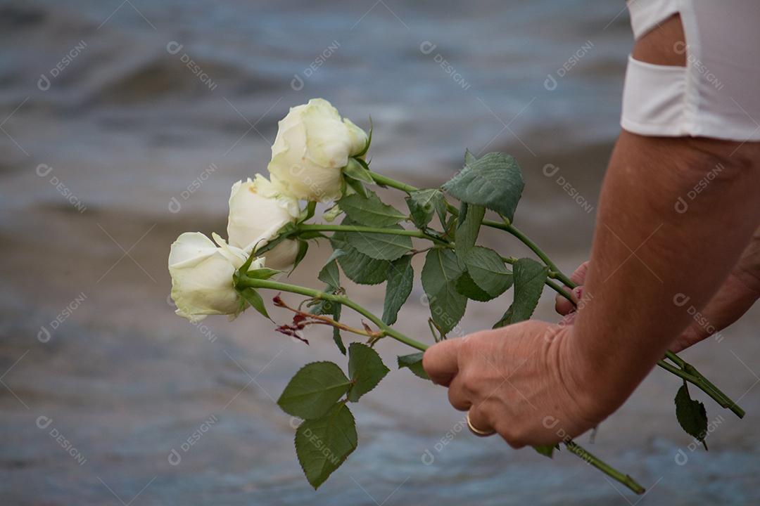 Foto Detalhe de Mãos Femininas Jogando Flores para Yemanjá Durante Festival de Yemanjá