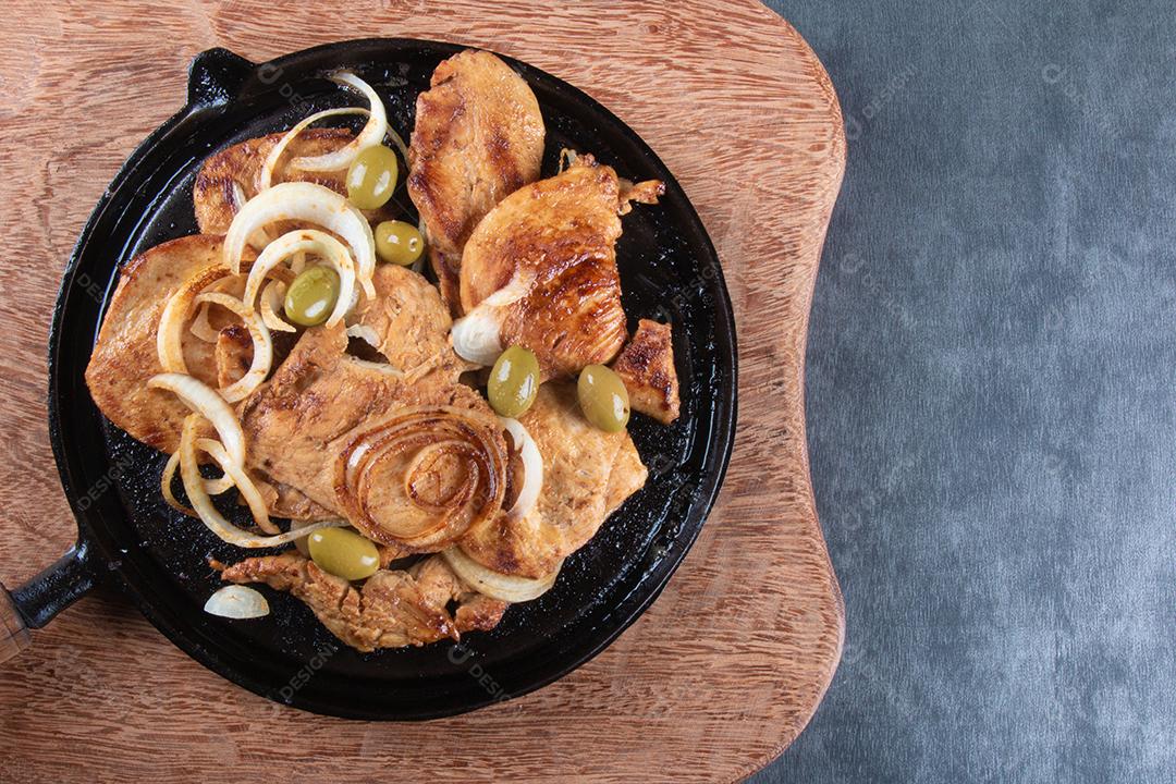 Fotos frango grelhado com cebola e azeitonas na vista superior da placa de ferro