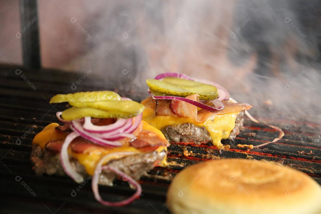 Hambúrguer. Hambúrguer brasileiro grelhado na parrilla com queijo derretido, bacon, cebola roxa e picles JPG