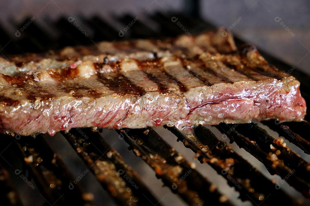 Linda picanha suculenta com marcas de grelha na parte superior da grelha com carvão brilhante no fundo.