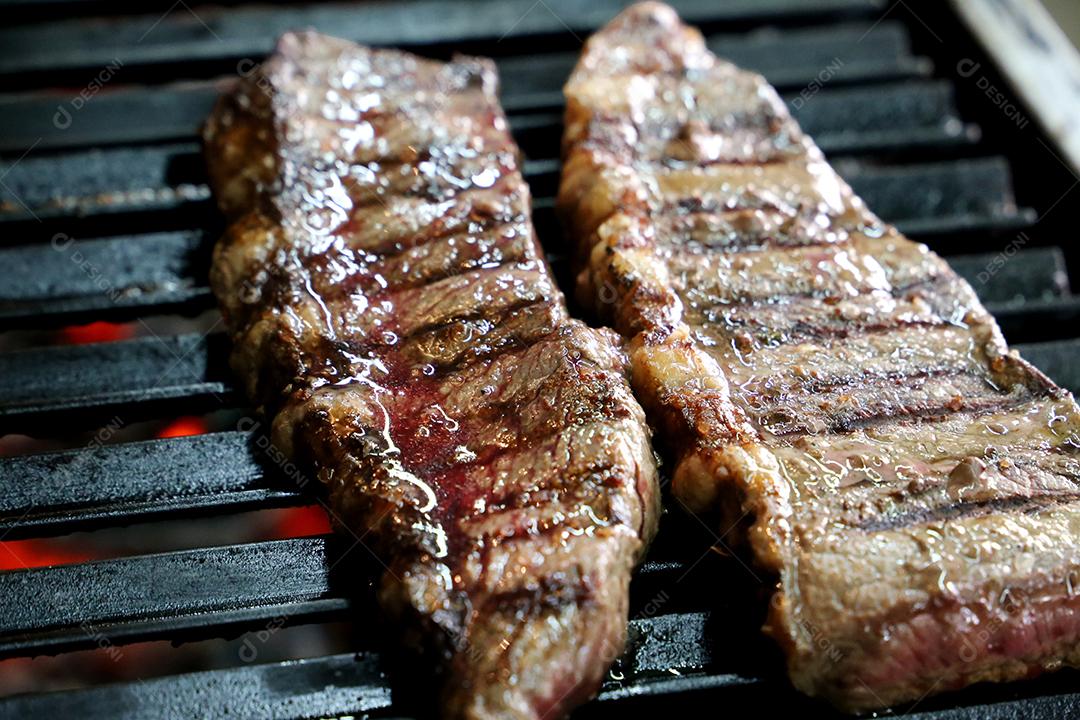 Linda picanha suculenta com marcas de grelha na parte superior da grelha com carvão brilhante no fundo.
