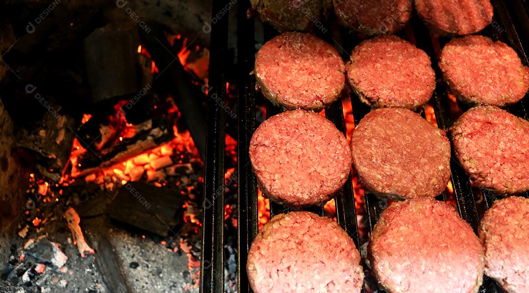 Muitos hambúrgueres na parrilla com carvão brilhante no fundo JPG