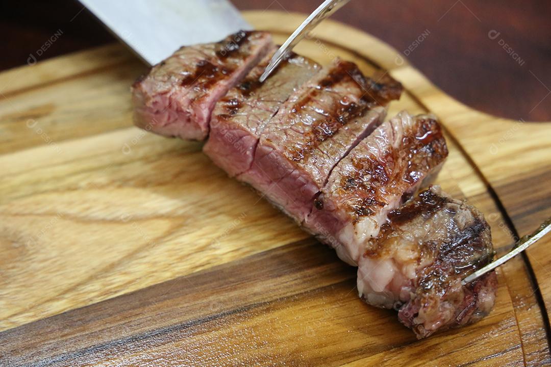 Chouriço. Churrasco brasileiro. Bife cortado em uma tábua de madeira JPG