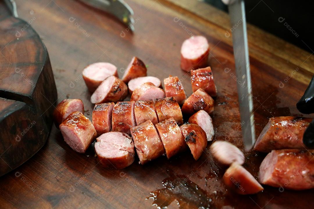salsicha fatiada em uma tábua de madeira rústica. Churrasco brasileiro JPG