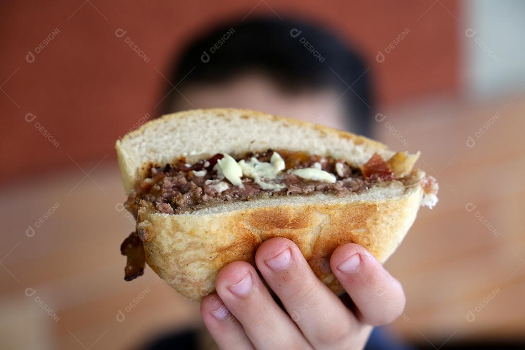 mão de criança segurando um hambúrguer na frente da câmera JPG