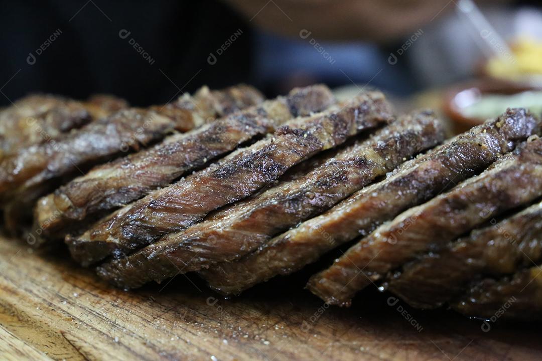 Cupim ou Cupim. Tradicional cordão brasileiro de boi Nelore cortado sob uma tábua de madeira com uma faca de churrasco JPG