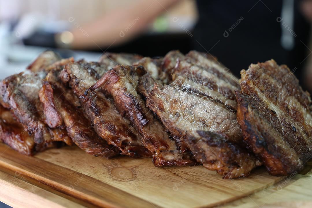 Muitos bifes cupim na mesa de madeira. Churrasco brasileiro JPG