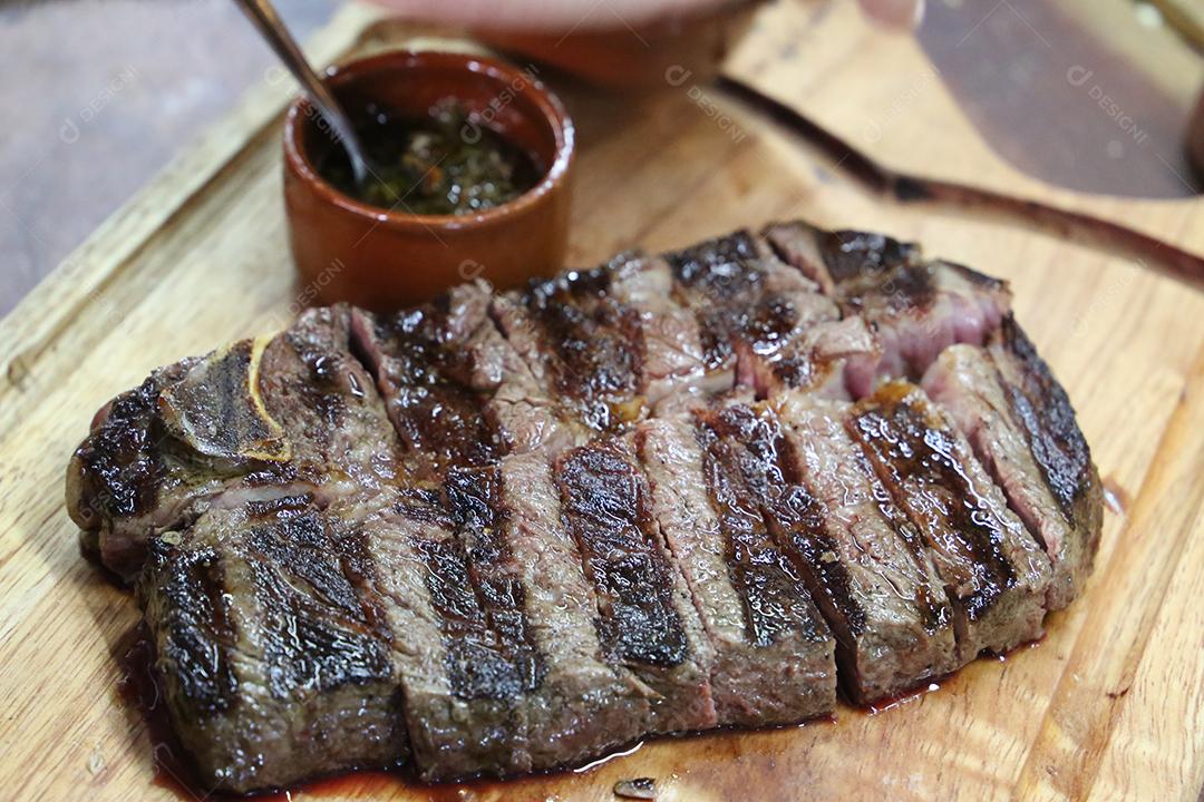 Costela curta ou Rib Premium. Bife grelhado em Parrilla argentina com marcas de grelha em uma tábua de madeira ao fundo. Comida brasileira JPG