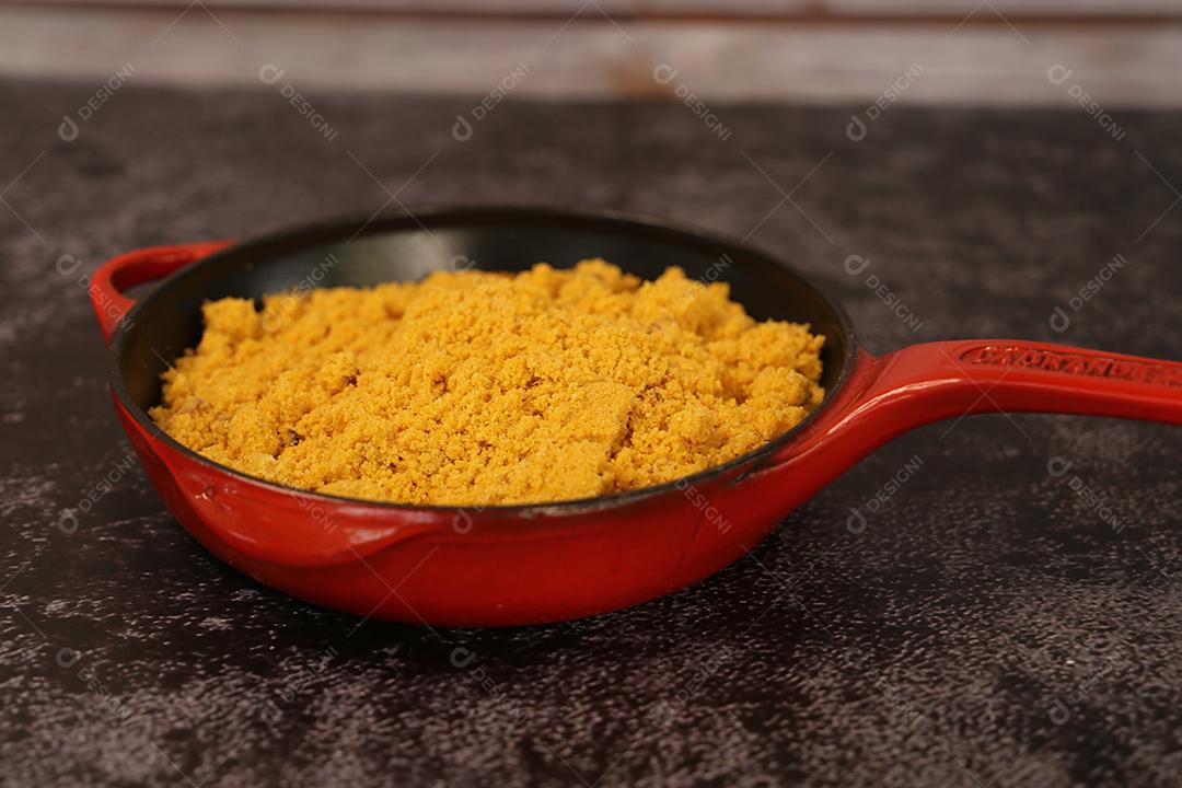 pote de ferro vermelho com Farofa. Comida tradicional brasileira. Em um fundo escuro JPG