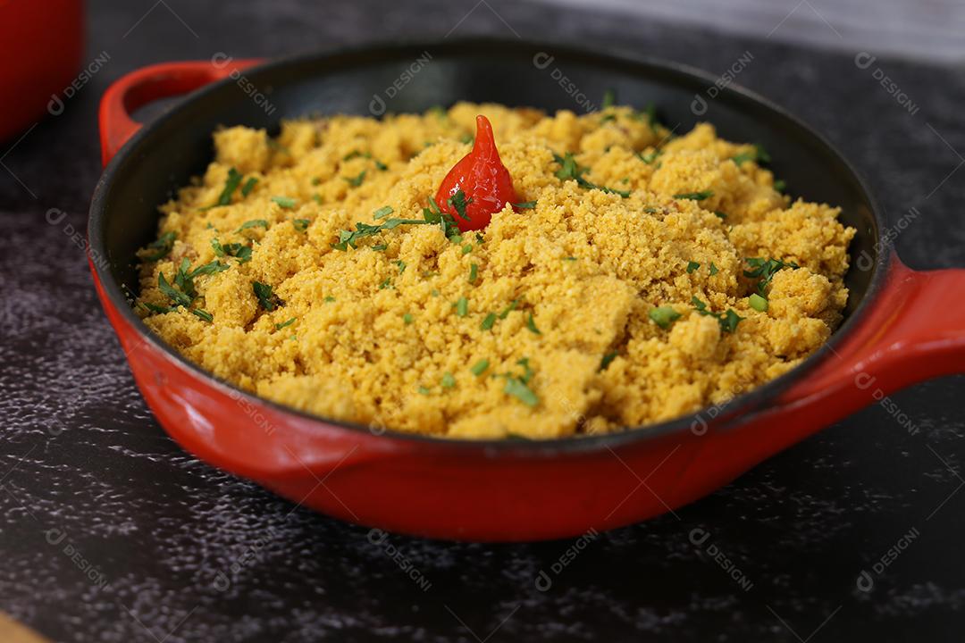 pote de ferro vermelho com Farofa. Comida tradicional brasileira. Em um fundo escuro JPG