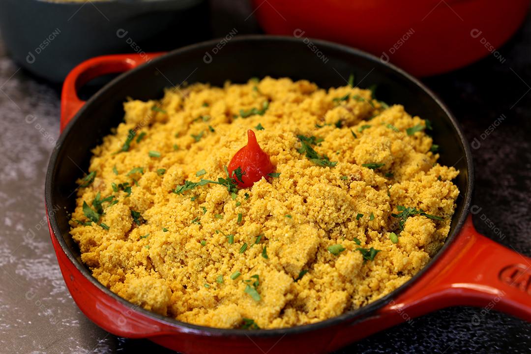 pote de ferro vermelho com Farofa. Comida tradicional brasileira. Em um fundo escuro JPG